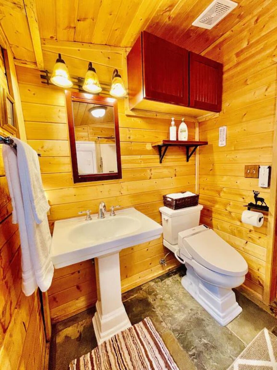 Cabin bathroom with pedestal sink and log walls