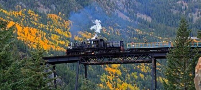 Historic steam train crossing a mountain trestle bridge